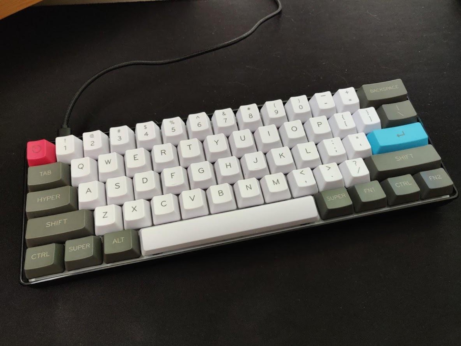 GK61 fitted with white, gray and red aftermarket keycaps on a dark desk mat