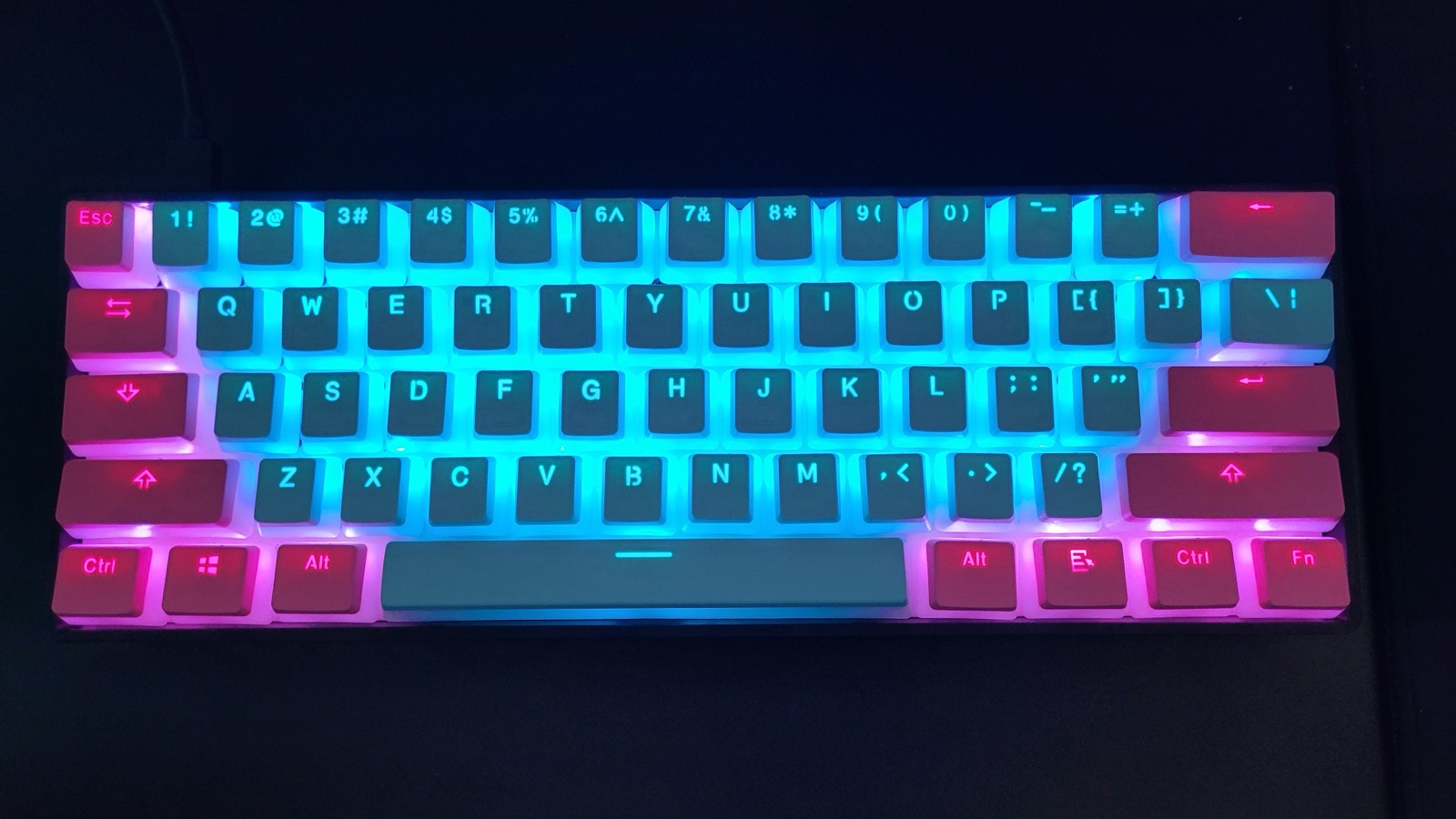 GK61 glowing cyan and pink in a dark room