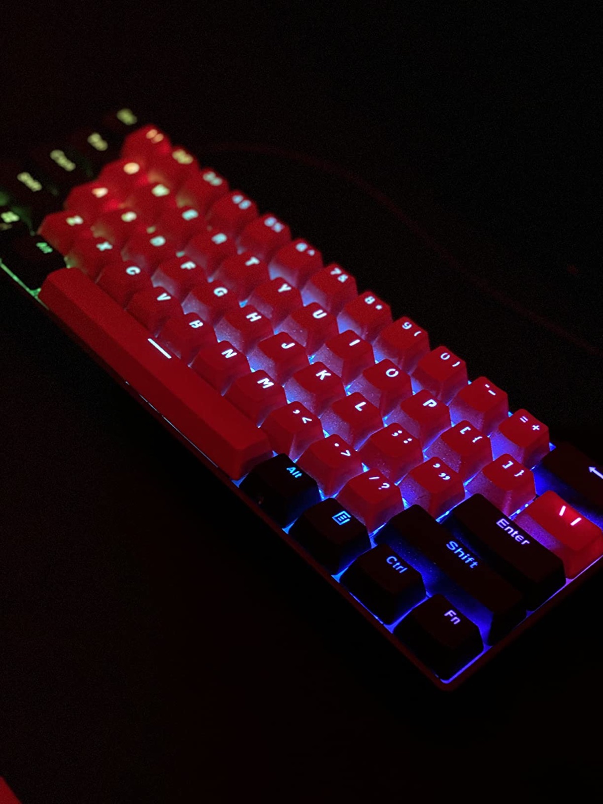 Red and black GK61 keycaps lit up at night